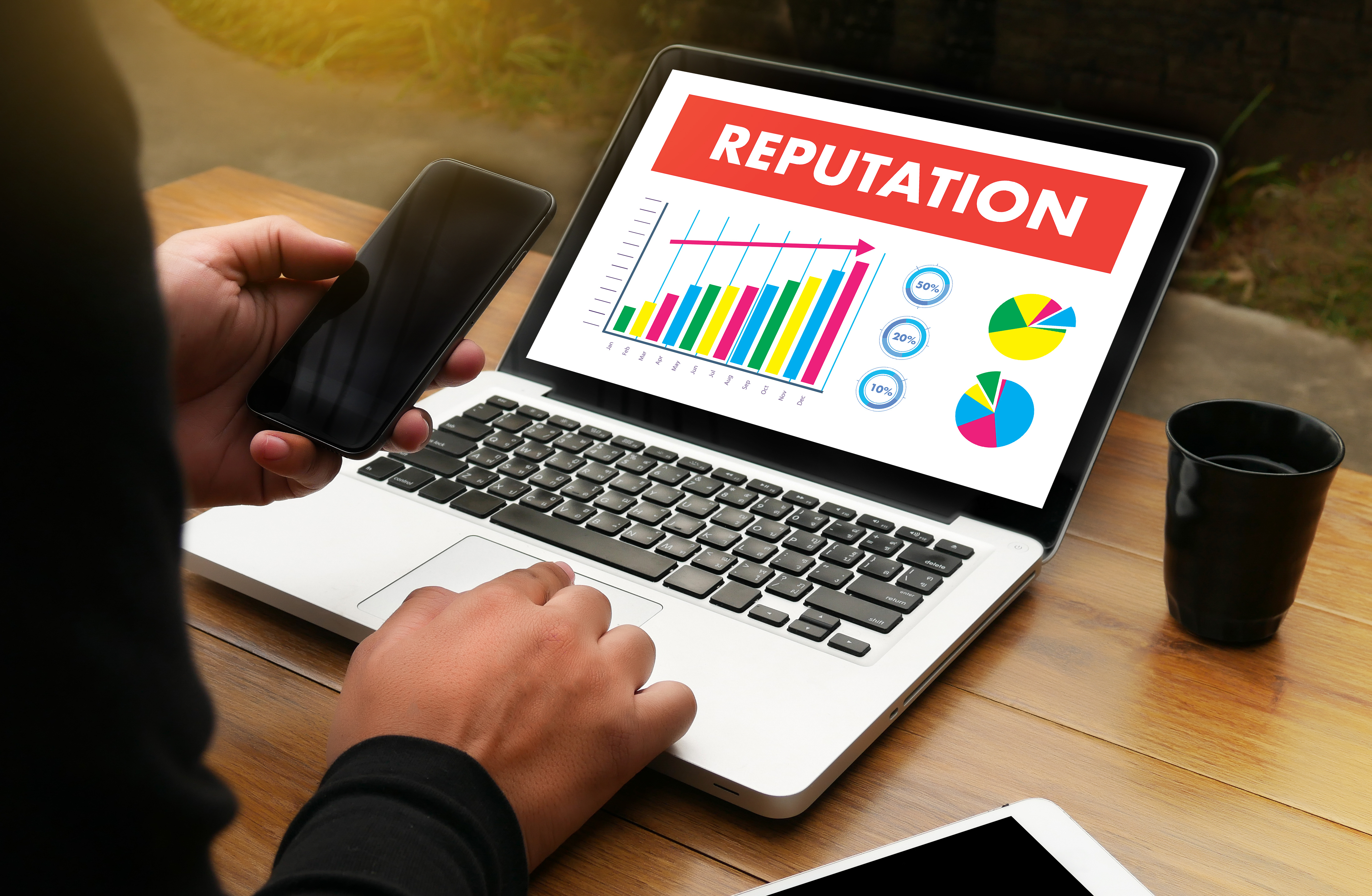 a laptop with a bar chart displayed along with the word 'reputation'